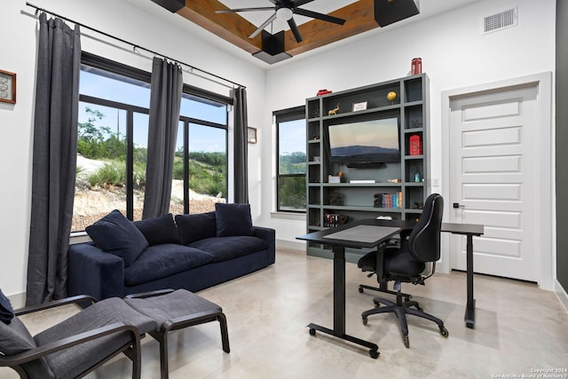 home office with plenty of natural light, visible vents, concrete floors, and a tray ceiling