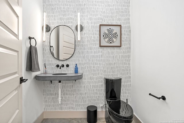 bathroom with an accent wall, baseboards, and wallpapered walls