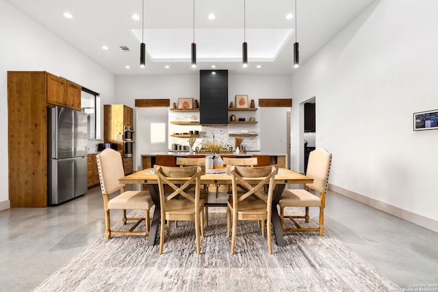 dining space featuring a tray ceiling, recessed lighting, baseboards, concrete flooring, and a towering ceiling