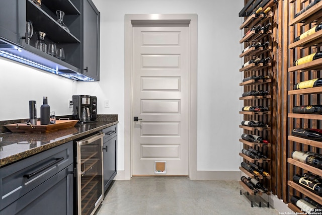 bar with baseboards, a bar, beverage cooler, and finished concrete flooring