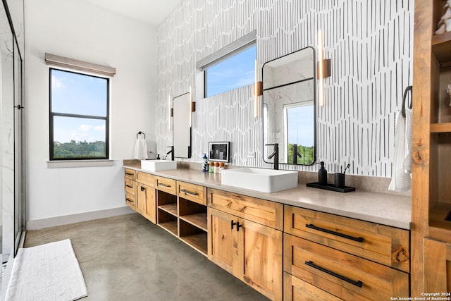 full bath featuring double vanity, wallpapered walls, baseboards, and a sink