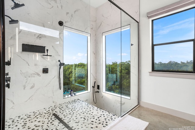 full bathroom with a marble finish shower, baseboards, and a wealth of natural light