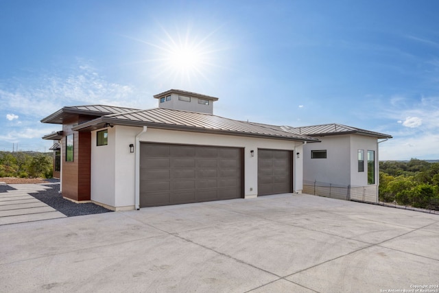 exterior space featuring stucco siding, driveway, a standing seam roof, metal roof, and a garage