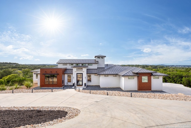 view of front of house featuring metal roof, concrete driveway, stucco siding, and a standing seam roof