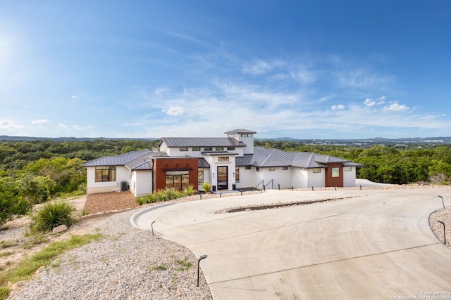 view of front of home with a forest view, metal roof, curved driveway, and a standing seam roof