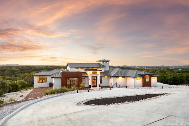 view of front of property featuring metal roof, curved driveway, cooling unit, and a standing seam roof