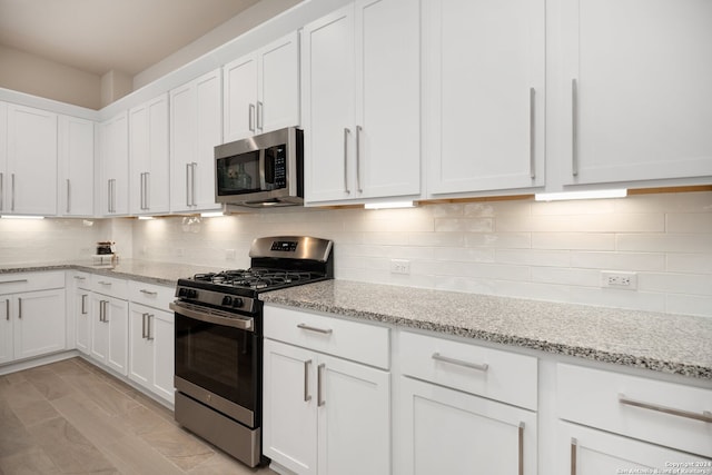 kitchen with white cabinetry, appliances with stainless steel finishes, tasteful backsplash, and light stone counters