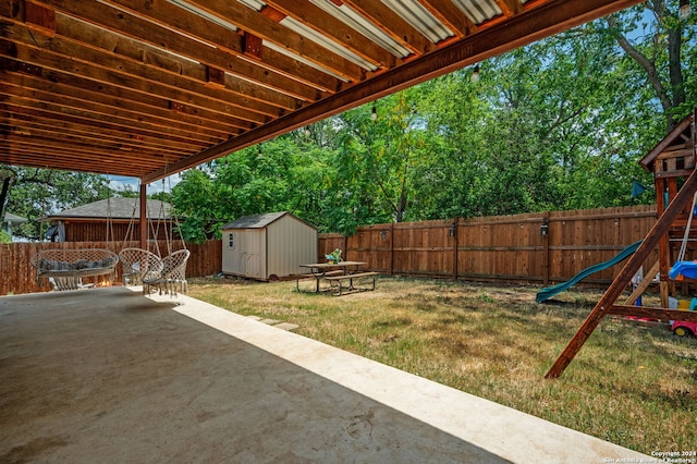 view of yard featuring a storage unit, a playground, and a patio area