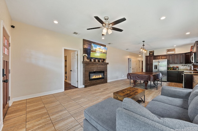 living room with ceiling fan, light tile patterned floors, and a tile fireplace