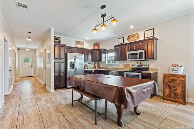 kitchen featuring a wealth of natural light, light tile patterned flooring, pendant lighting, and stainless steel appliances