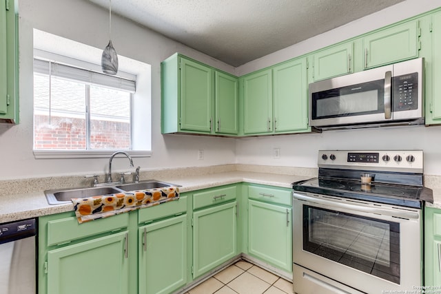 kitchen featuring appliances with stainless steel finishes, sink, a textured ceiling, light tile patterned floors, and green cabinetry