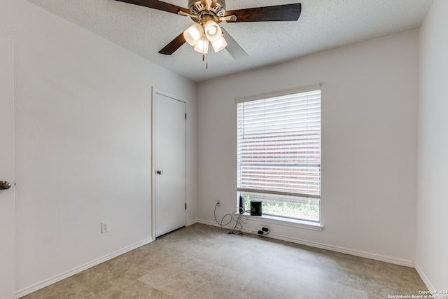 tiled empty room with ceiling fan and a textured ceiling