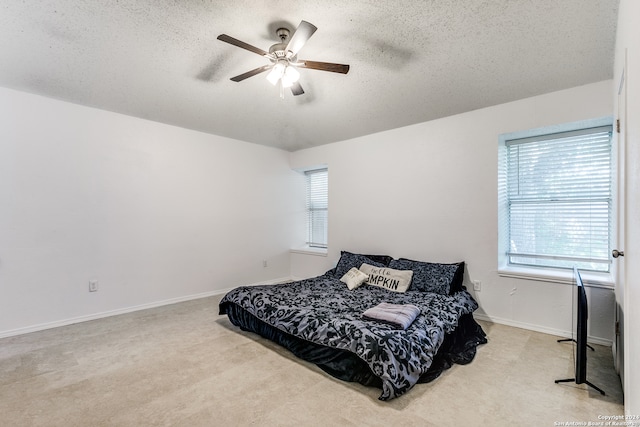 bedroom featuring a textured ceiling, ceiling fan, and light carpet