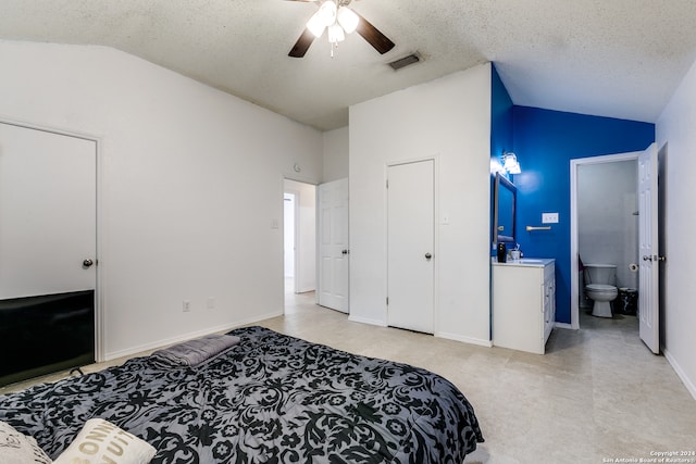 bedroom featuring ceiling fan, vaulted ceiling, a textured ceiling, and ensuite bathroom