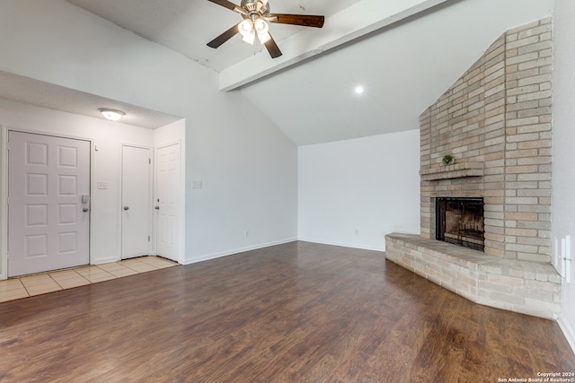 unfurnished living room with light hardwood / wood-style flooring, lofted ceiling with beams, brick wall, ceiling fan, and a brick fireplace