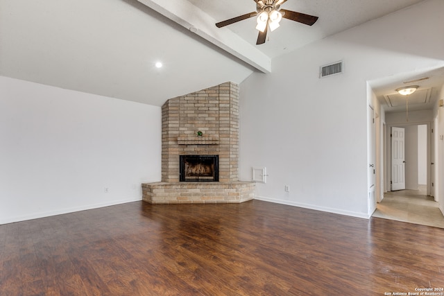 unfurnished living room featuring ceiling fan, beam ceiling, hardwood / wood-style floors, and brick wall