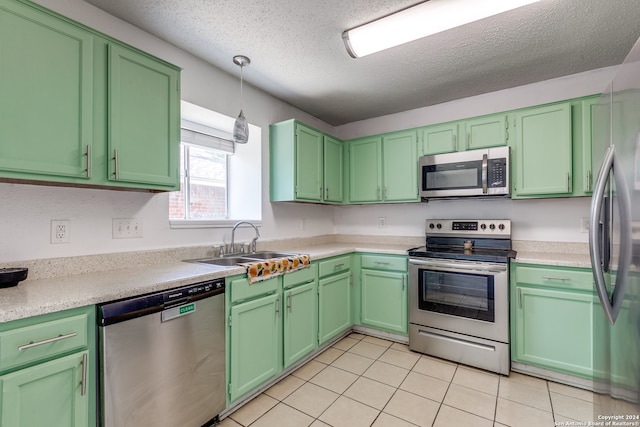 kitchen featuring sink, appliances with stainless steel finishes, a textured ceiling, light tile patterned floors, and hanging light fixtures