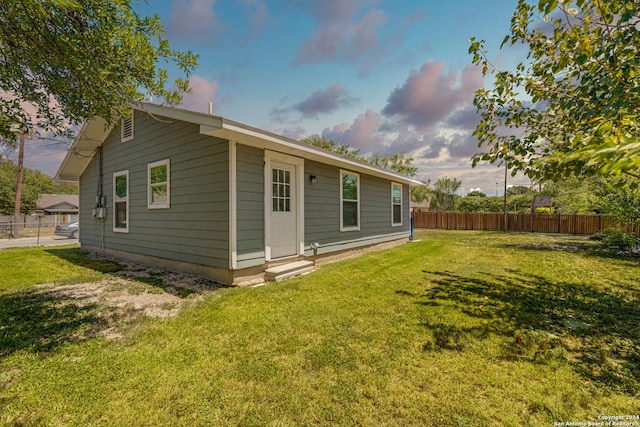 rear view of property featuring a yard and fence