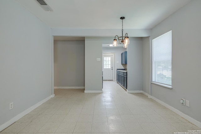 empty room with visible vents, baseboards, and a notable chandelier