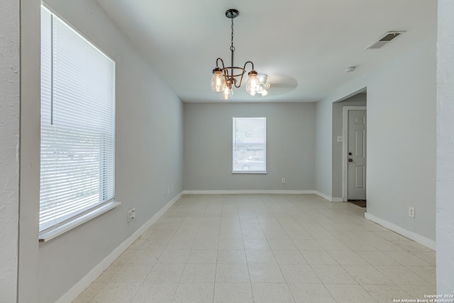 tiled spare room with an inviting chandelier