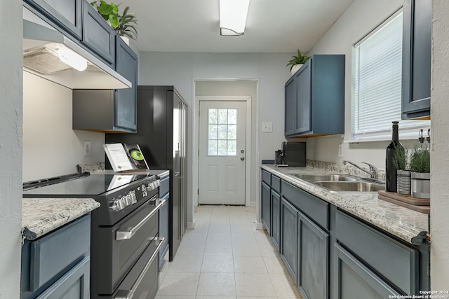 kitchen featuring custom range hood, sink, light stone counters, electric range, and light tile patterned floors