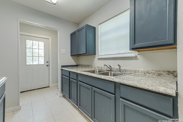 kitchen with a sink, baseboards, gray cabinets, and light countertops