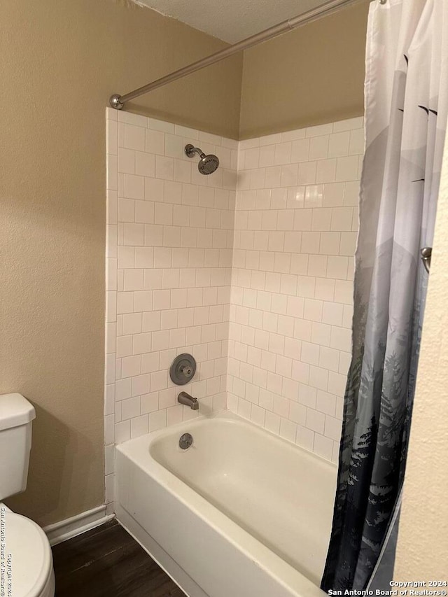 2542 Babcock Rd Unit E103, San Antonio, TX 78229 - bathroom with wood finished floors, toilet, a textured wall, baseboards, and shower / tub combo