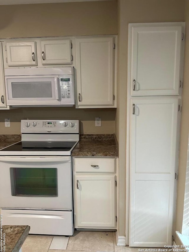 2542 Babcock Rd Unit E103, San Antonio, TX 78229 - kitchen with dark countertops, light tile patterned flooring, white cabinetry, and white appliances