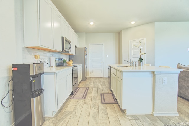 kitchen with decorative backsplash, a kitchen island with sink, appliances with stainless steel finishes, light hardwood / wood-style floors, and sink