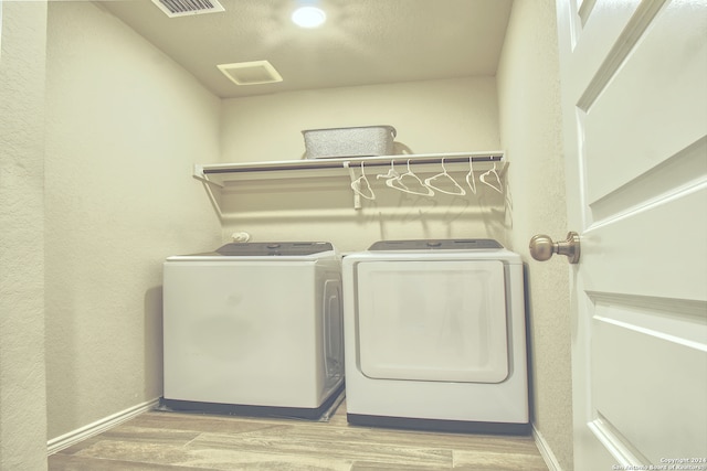 clothes washing area with light wood-type flooring and washing machine and dryer