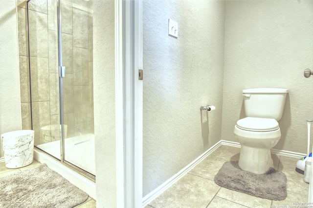 bathroom featuring toilet, a shower with door, and tile patterned floors