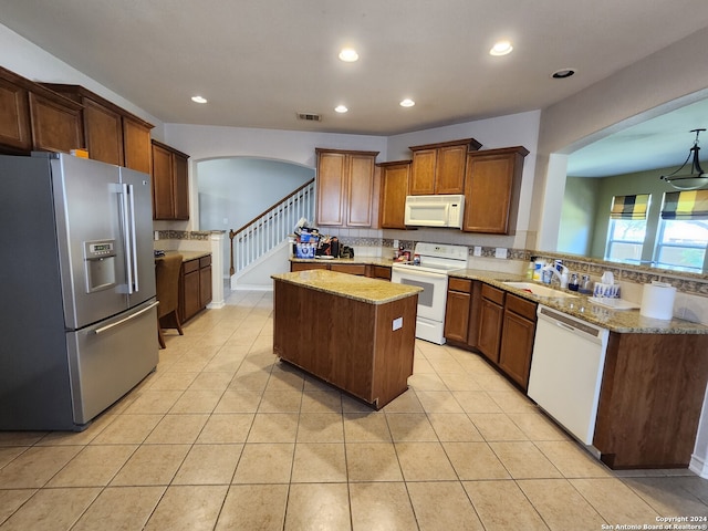 kitchen with kitchen peninsula, a center island, light stone counters, and white appliances