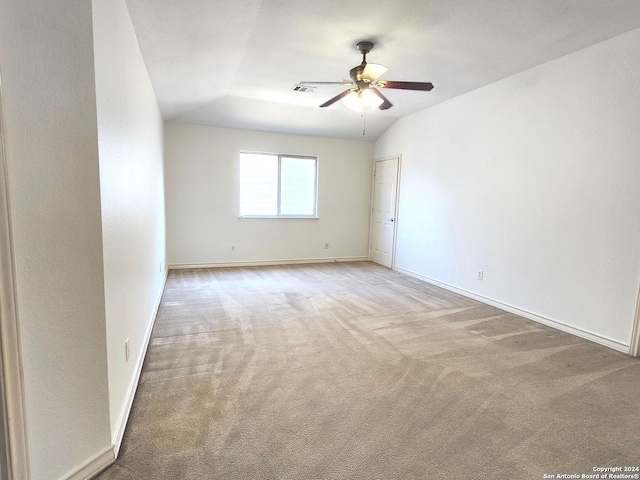 spare room featuring light carpet, lofted ceiling, and ceiling fan