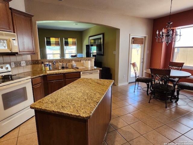 kitchen featuring white appliances, tasteful backsplash, light tile patterned flooring, hanging light fixtures, and a chandelier