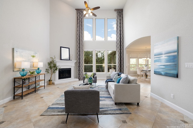 living room with a towering ceiling and ceiling fan with notable chandelier