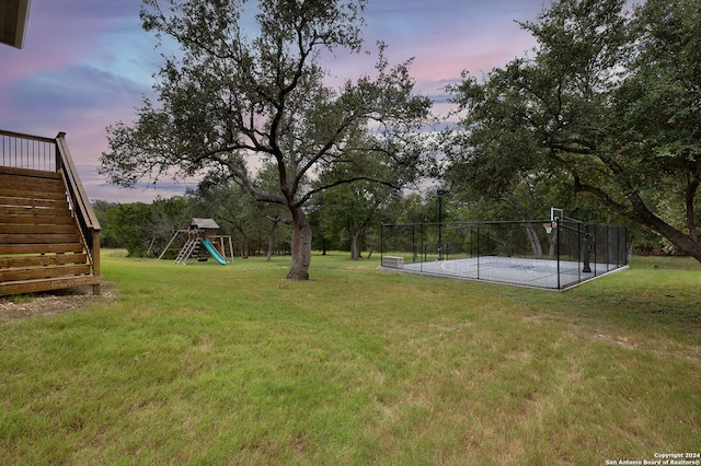 yard at dusk featuring a playground