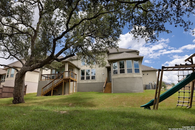 back of house featuring a playground and a lawn