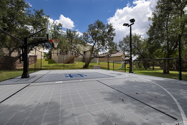 view of basketball court featuring a playground and a lawn