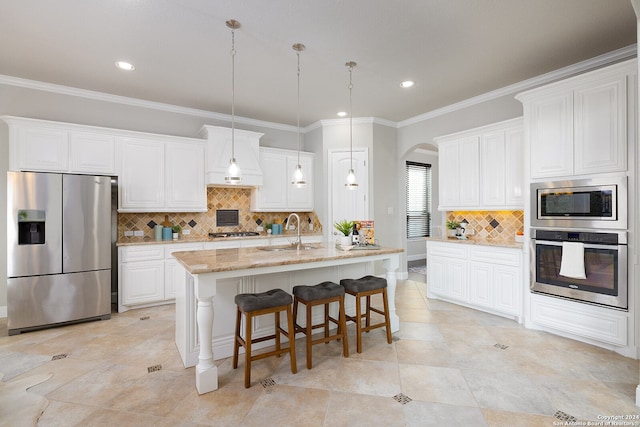 kitchen with appliances with stainless steel finishes, light stone counters, white cabinetry, sink, and decorative backsplash