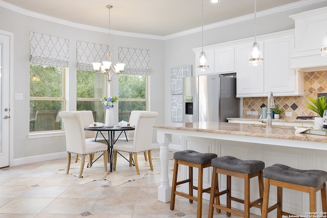 kitchen featuring pendant lighting, a wealth of natural light, and stainless steel refrigerator with ice dispenser