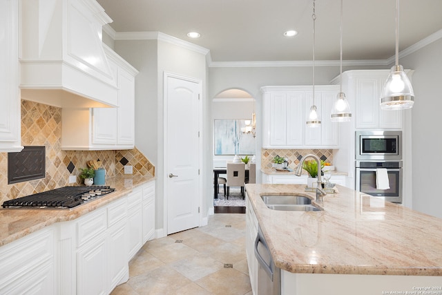 kitchen with backsplash, decorative light fixtures, stainless steel appliances, sink, and a kitchen island with sink