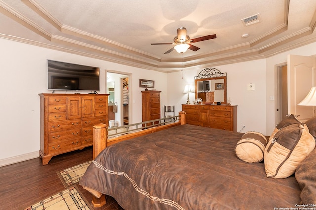 bedroom featuring crown molding, visible vents, a tray ceiling, and wood finished floors