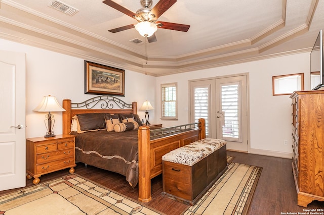 bedroom with visible vents, ornamental molding, a tray ceiling, and wood finished floors