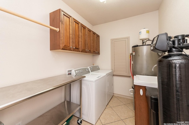 washroom with water heater, cabinet space, washing machine and clothes dryer, and light tile patterned flooring