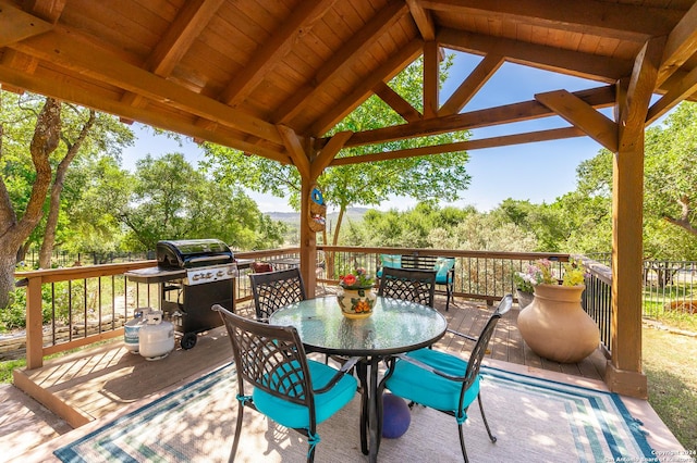 view of patio featuring a wooden deck, area for grilling, fence, outdoor dining area, and a gazebo