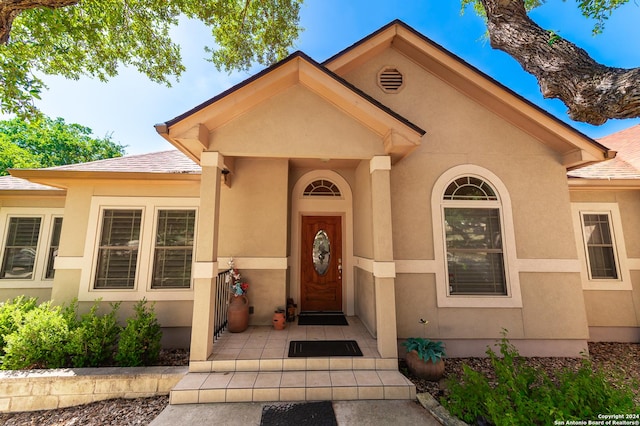 property entrance featuring roof with shingles and stucco siding