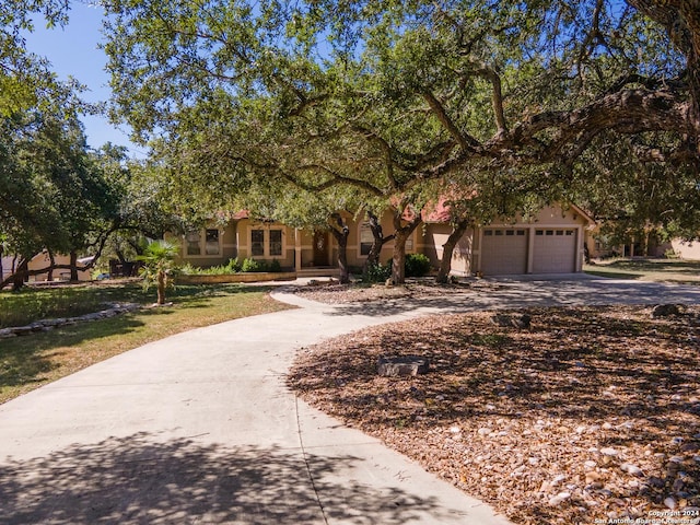 obstructed view of property featuring a front lawn, driveway, an attached garage, and stucco siding