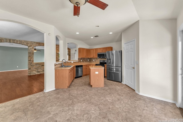 kitchen with light wood-type flooring, appliances with stainless steel finishes, a center island, and ceiling fan