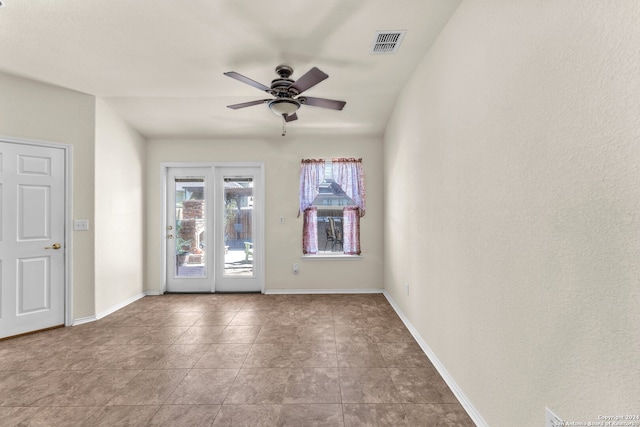 tiled empty room featuring ceiling fan and french doors