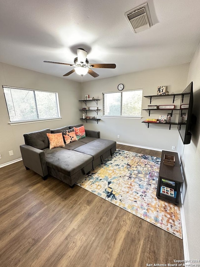 living room featuring baseboards, wood finished floors, visible vents, and a ceiling fan